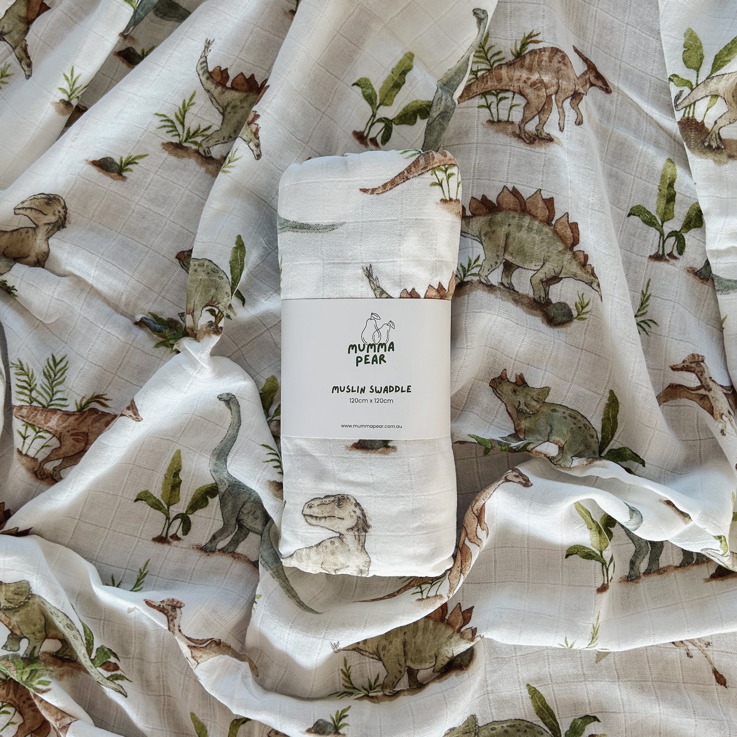 Muslin baby swaddle with white background and blue, green and brown dinosaur print.